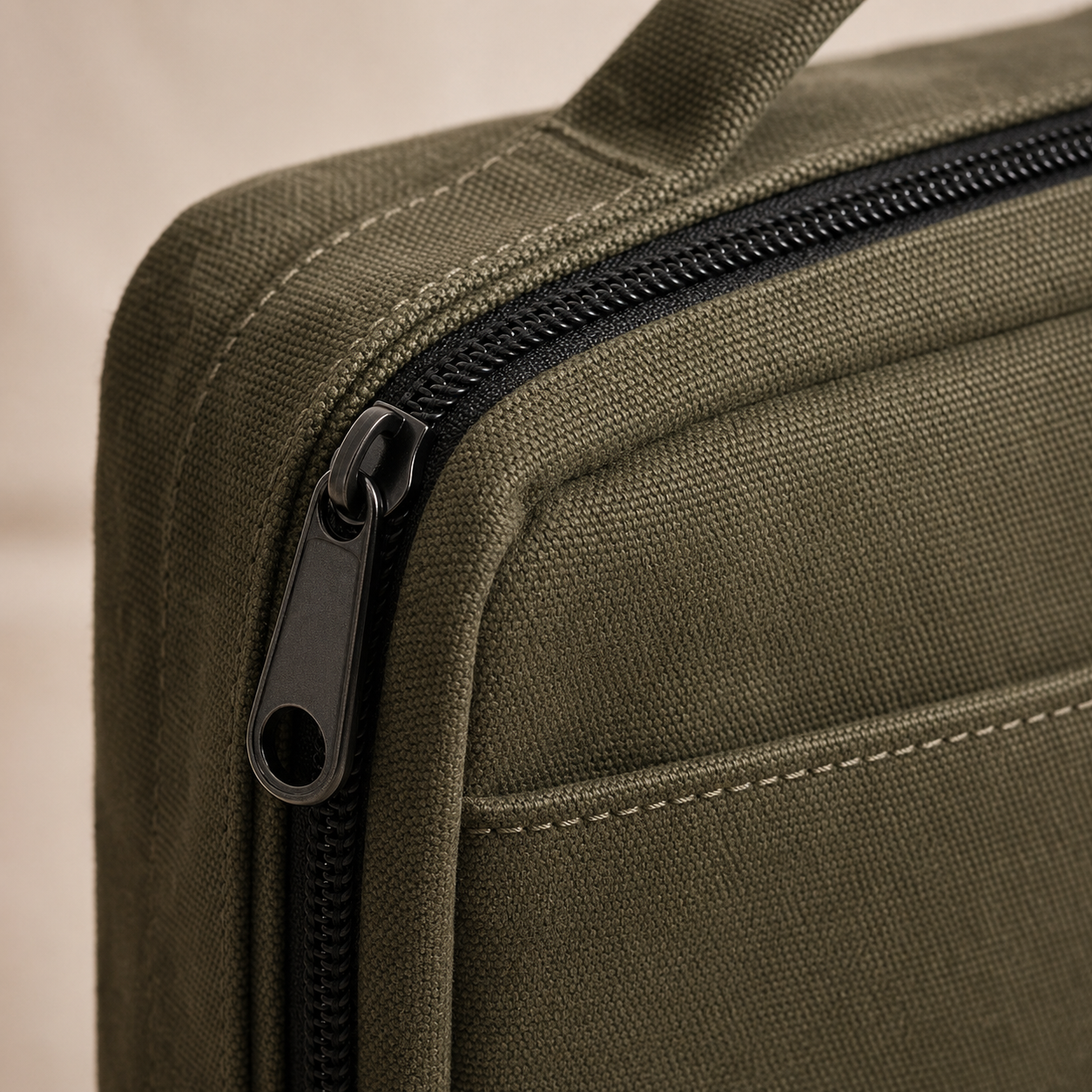 Close detail of canvas texture, stitching, and zipper pull.